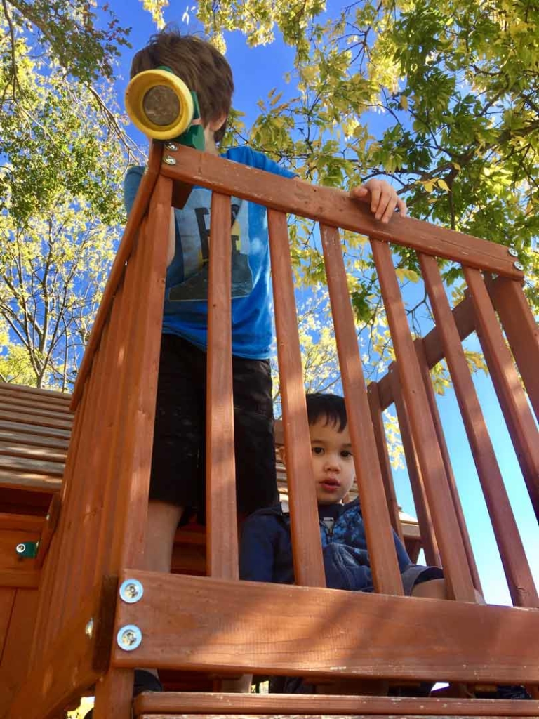 Two children with autism play in a large wooden playground during an ABA therapy session