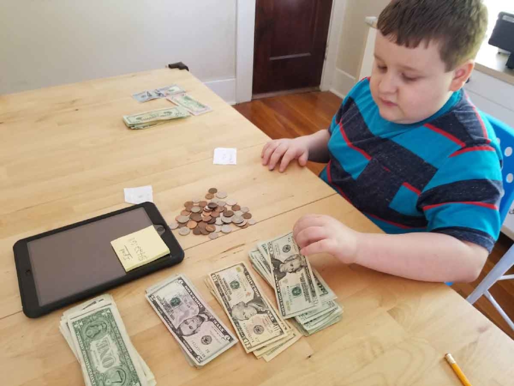 A child with autism counts different kinds of money during a life skills session
