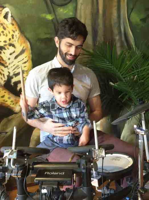 An ABA therapy technician shows a child with autism how to play the drums