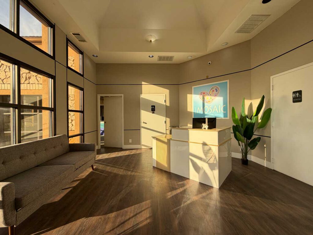 The sunlit reception lobby at Bright Mosaic in Sherman, TX, featuring a modern welcome desk, comfortable seating, and the Bright Mosaic logo.