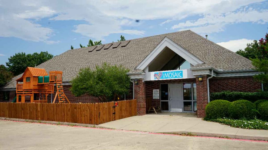 Front exterior of the Mosaic Autism Center in Denton on Bonnie Brae St., featuring a secure playground and entrance for ABA, Speech, and OT therapy services.
