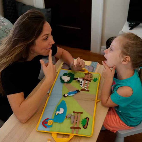A young girl mirrors her therapist's mouth movements during a individual pediatric speech therapy session.